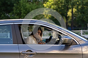 Crying young girl read message in mobile phone. Frustrated upset young woman at driver seat in car