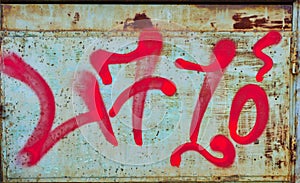 Cryptic Red Graffiti on Rusted Metal Sheet photo