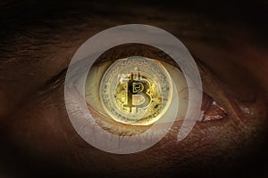 Crypto currency Gold bitcoin. Macro shooting bitcoins. Eye of a man with a bitcoin coin reflected in a student.