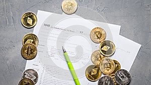 Crypto currency: Pages of the tax form 1040 and a scatter of coins bitcoin, ethereum.