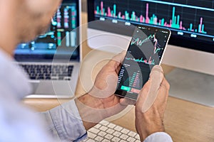 Crypto trader broker using phone app analyzing stock market on cell phone.