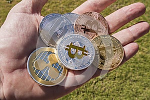 Cryptocurrency coins in a hand; Bitcoin, Ripple, Dash