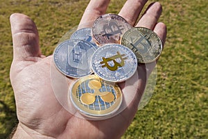 Cryptocurrency coins in a hand; Bitcoin, Ripple, Dash