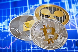 Cryptocurrency coins over trading graphic screen; Bitcoin, Ether