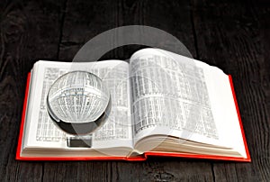 Crystal ball and book of ephemeris on blurred old black wooden background