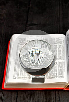 Crystal ball and opened book of ephemeris on blurred black wooden background photo