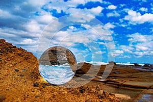 Crystal ball with the reflection of the sandy beach on a hot summer day