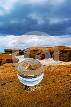 Crystal ball with the reflection of the sandy beach on a summer day