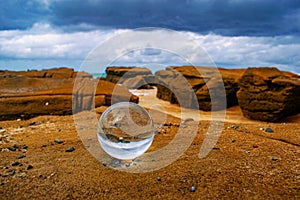 Crystal ball with the reflection of the sandy beach on a summer day