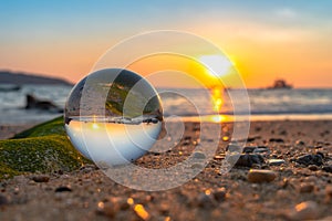 A crystal ball rests on the sandy pebbles of Kalim Beach.