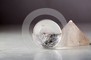 Crystal ball and rock crystal pyramid against a dark background