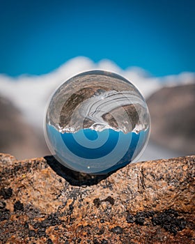 Crystal ball on a rock with reflection of a lake and dirt road against a blurry background