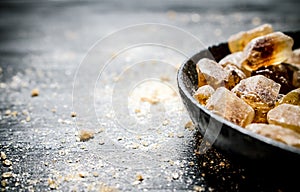 Crystal brown sugar. On black rustic background.