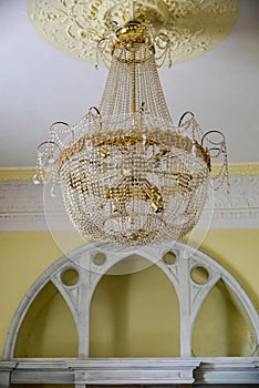 Crystal chandelier with golden details. Glass drops furniture elements