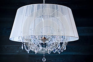 A crystal chandelier with a white shade