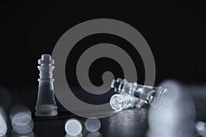 Crystal chess king piece in front of the defeated enemies on a black background with copy space