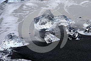 Crystal Clear and Blue Ice Floes on a Black Sand Beach on the Iceland Coast in heavy surf