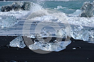 Crystal Clear and Blue Ice Floes on a Black Sand Beach on the Iceland Coast in heavy surf