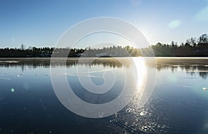 Crystal clear frozen lake in Northern Sweden - ice like big mirror. Low sun lights with warm light at very cold winter day