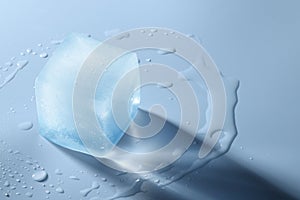 Crystal clear ice cube on light blue background, space for text