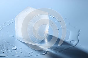 Crystal clear ice cube on light blue background, space for text