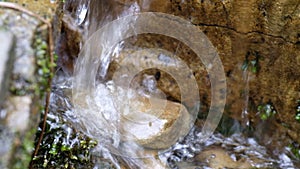 Crystal-clear mountain water flowing down over brown stone in macro