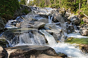 Krištáľovo čistá horská voda tečúca po kameňoch. Detailný záber na vodnú kaskádu Studeného potoka, národný park Vysoké Tatry, Slovensko