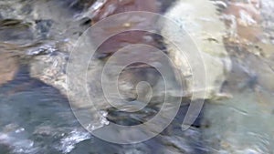 Crystal clear river water rapids flowing over a Cobble Stone and pebbles