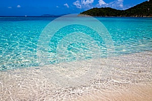 Crystal clear water laps the white sand of Hawksnest Bay Beach