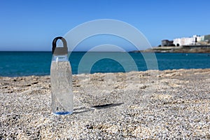 Crystal clear water in a plastic bottle stands on the beach. photo