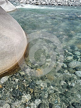 Crystal clear water river with rocks during sunny day