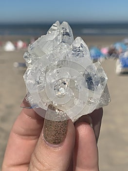 Crystal cluster in womans hand on the beach sand water gems gemstones points nature
