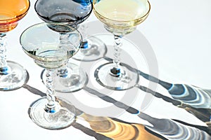 Crystal colorful stemware set with reflection over white background. Colourful elite set of empty alcohol liquor glasses