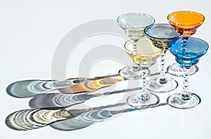 Crystal colorful stemware set with reflection over white background. Colourful elite set of empty alcohol liquor glasses