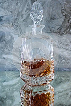 Crystal decanter with whiskey on a gray background
