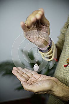 Crystal Dowser Holding Hand Pendulum dowsing is a form of divination