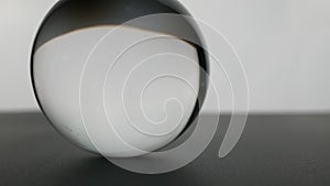 Crystal glass ball sphere transparent rolling on grey gradient background.