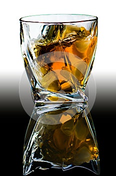 Crystal glass with curved edges with old Scotch whiskey and pieces of ice.