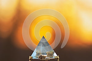 Crystal glass pyramid on a background of a sunset blurred sun and sky for relaxation meditation and divination