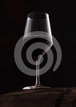 Crystal glass of red wine on top of wooden barrel on black