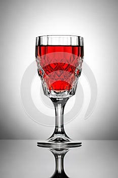 Crystal glass of red wine on a white table.