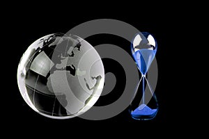 Crystal globe and blue hourglass on black background