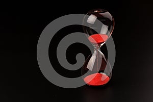 Crystal hourglass on black background as a concept of passing time for business term, urgency and outcome of time