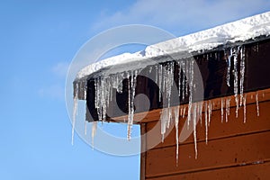 Crystal icicles hanging down and melting on house roof