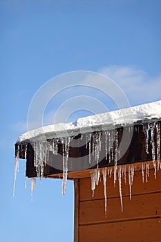 Crystal icicles hanging down and melting on house roof