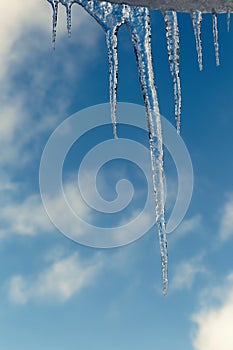 Crystal icicles on roof over blue sky