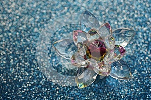 Crystal lotus on blue shiny sequins table. Vishuddha chakra symbol. Reiki meditation