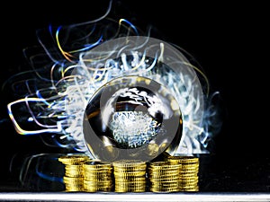 Crystal magical glass ball on stack of golden coins, abstract light painting on dark background. Forecasting money and profit gain