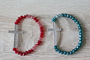 Crystal rosaries with a metal cross on wood background.