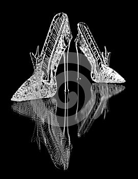 Un par de zapatos de cristal sobre un fondo negro con reflejo